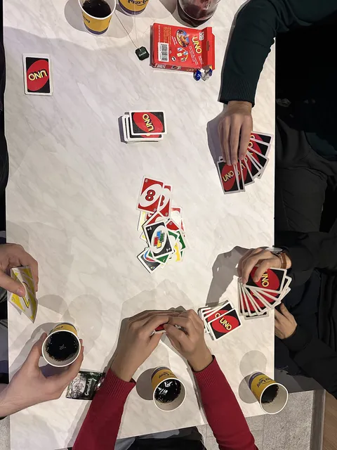 Uno regler dansk: spillere med Uno-kort omkring et bord, set ovenfra