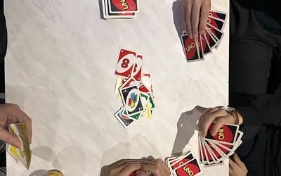 Uno regler dansk: spillere med Uno-kort omkring et bord, set ovenfra